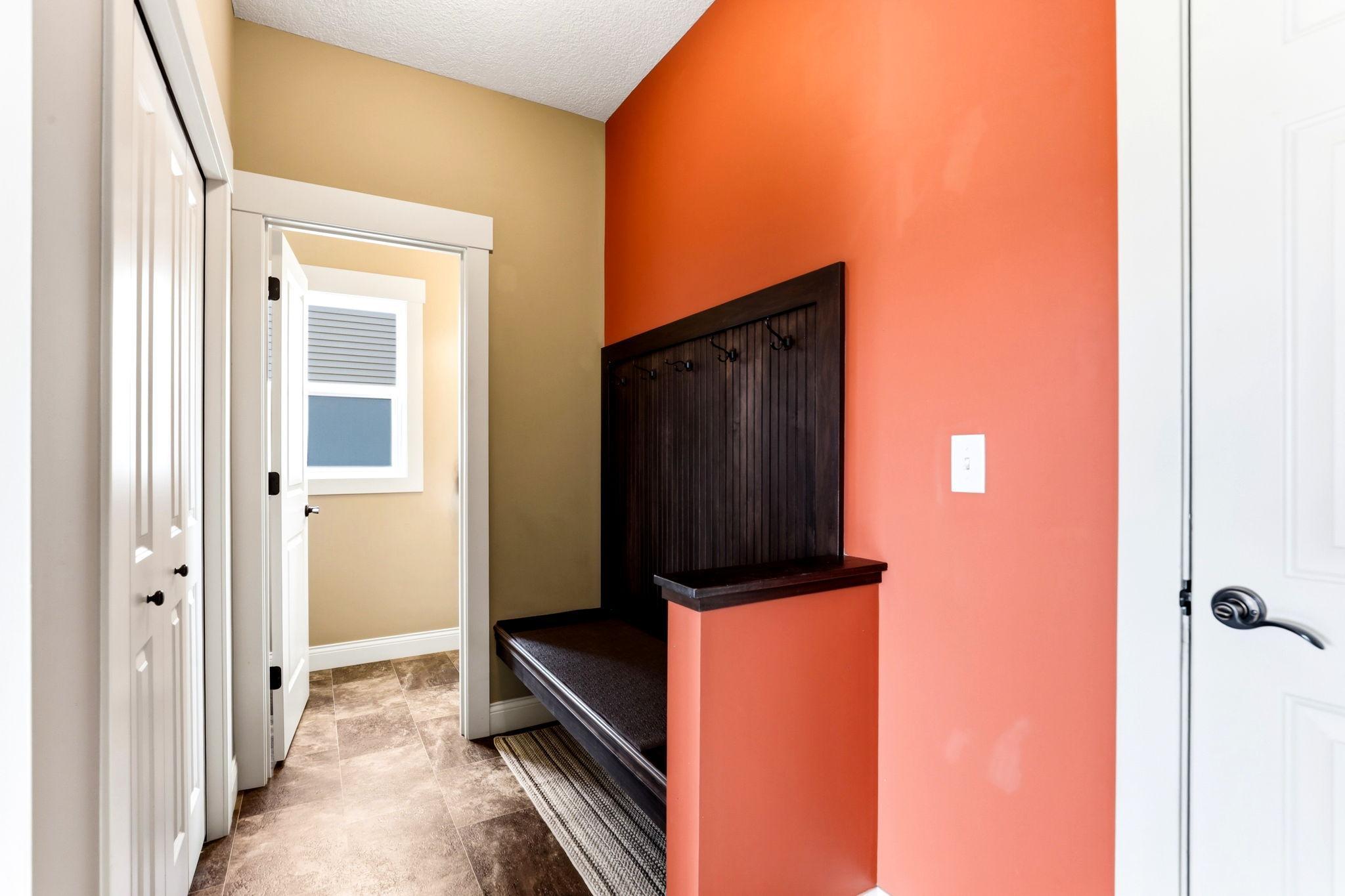 Functional mudroom with coat hooks, built-in bench, coat closet, and adjacent half bath.