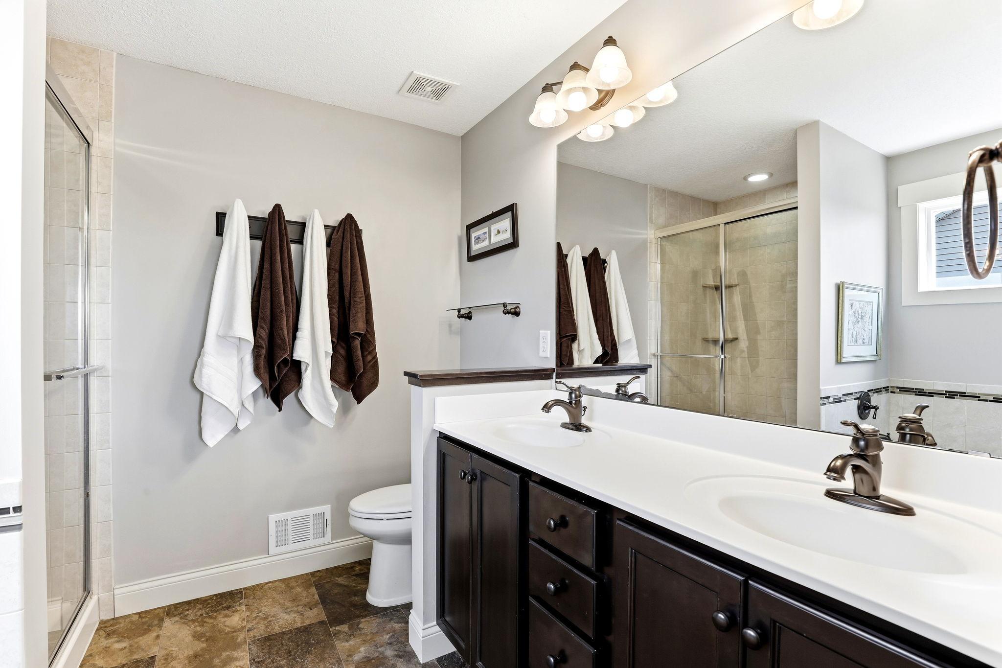 Private primary ensuite featuring dual sinks, ample vanity storage, and a glass shower enclousre.