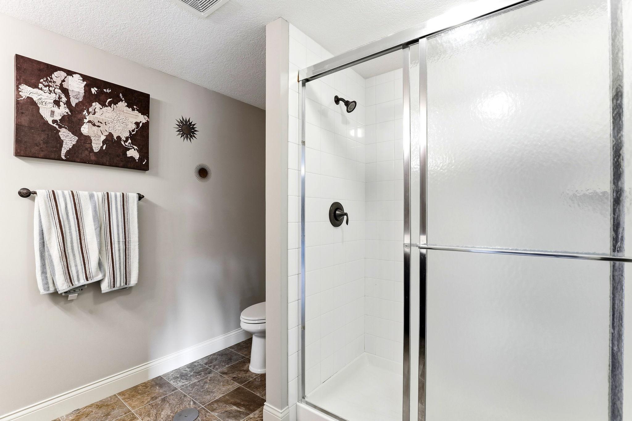 Lower-level full bath featuring tile-look flooring and a glass-door walk-in shower.