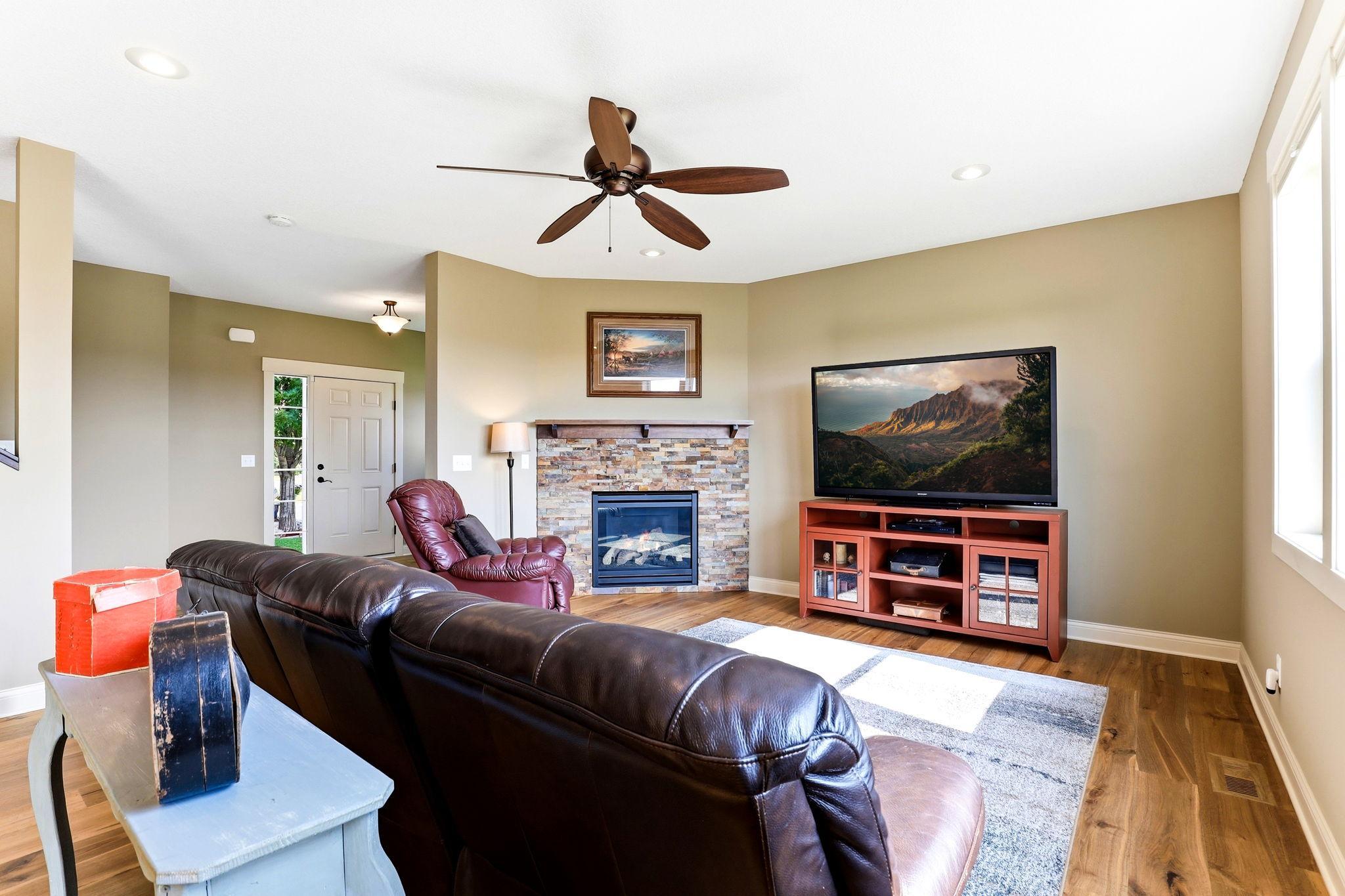Cozy living room with stone gas fireplace, wood mantle, TV outlets, and warm natural light.