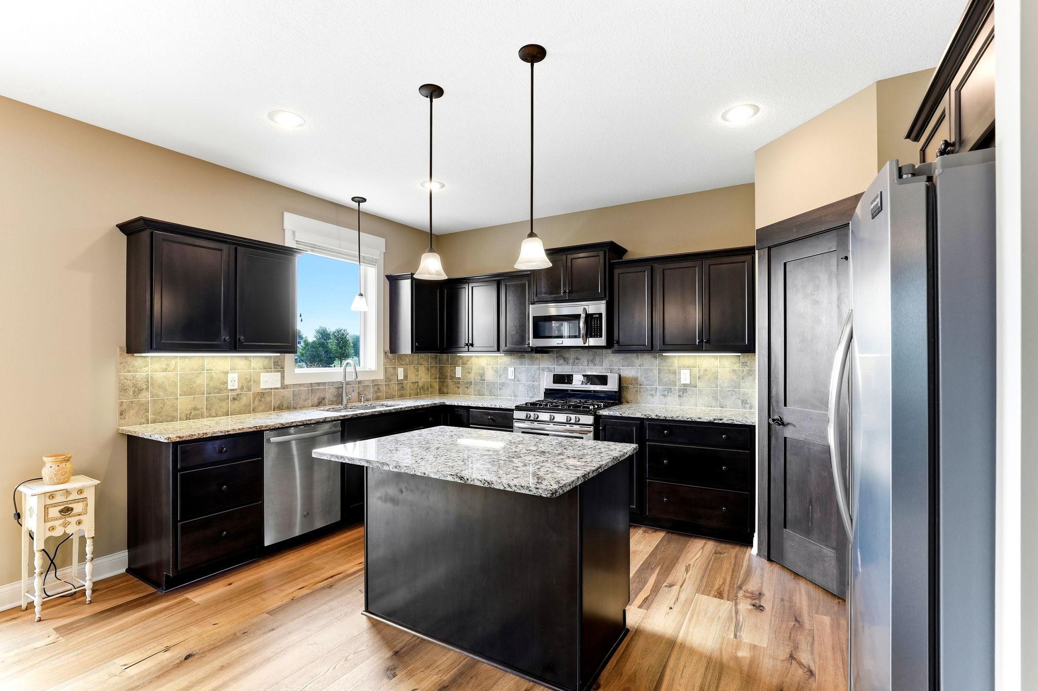 Spacious kitchen featuring under-cabinet lighting, corner pantry, and sunny sink-side window offering a scenic view.