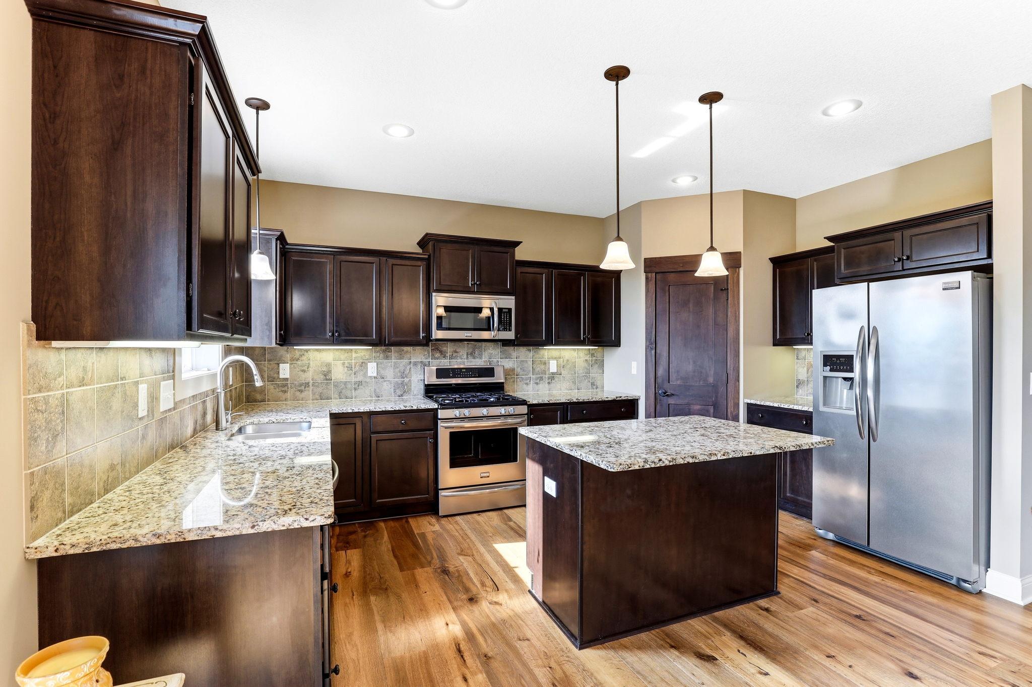 Chef's kitchen featuring granite countertops, stainless steel appliances, center island, with pendant lighting.
