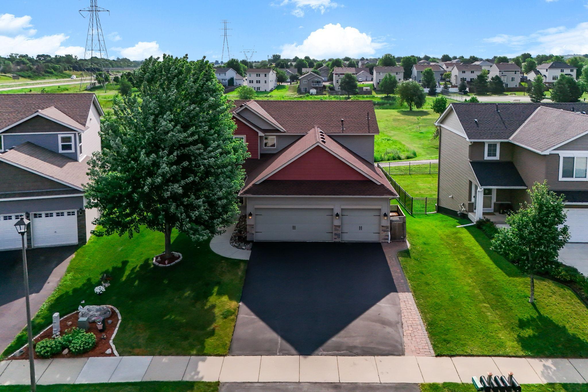 Aerial view showcasing beautiful curb appeal, mature trees, and attached 3-car garage.