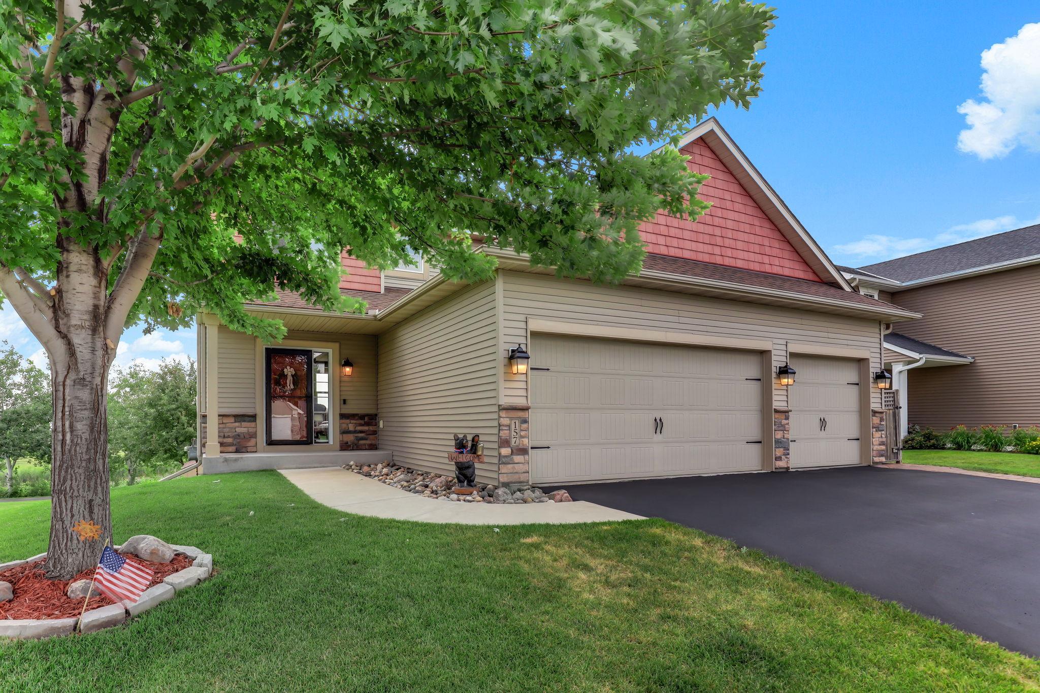 Welcoming front entrance featuring stone accents, charming covered porch, and manicured landscaping.