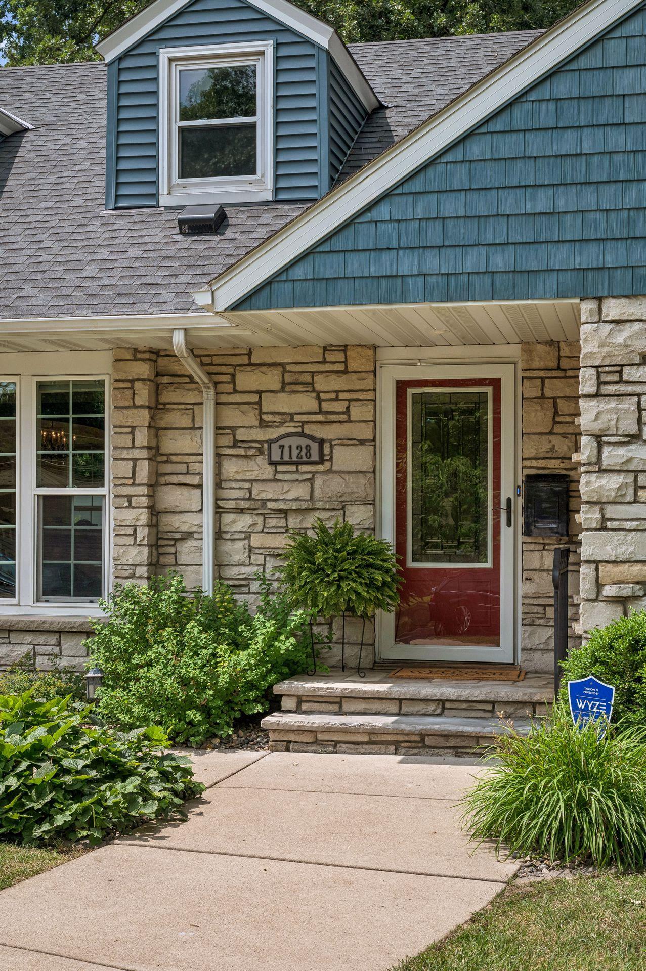 An inviting front entrance with stone and new concrete walkway