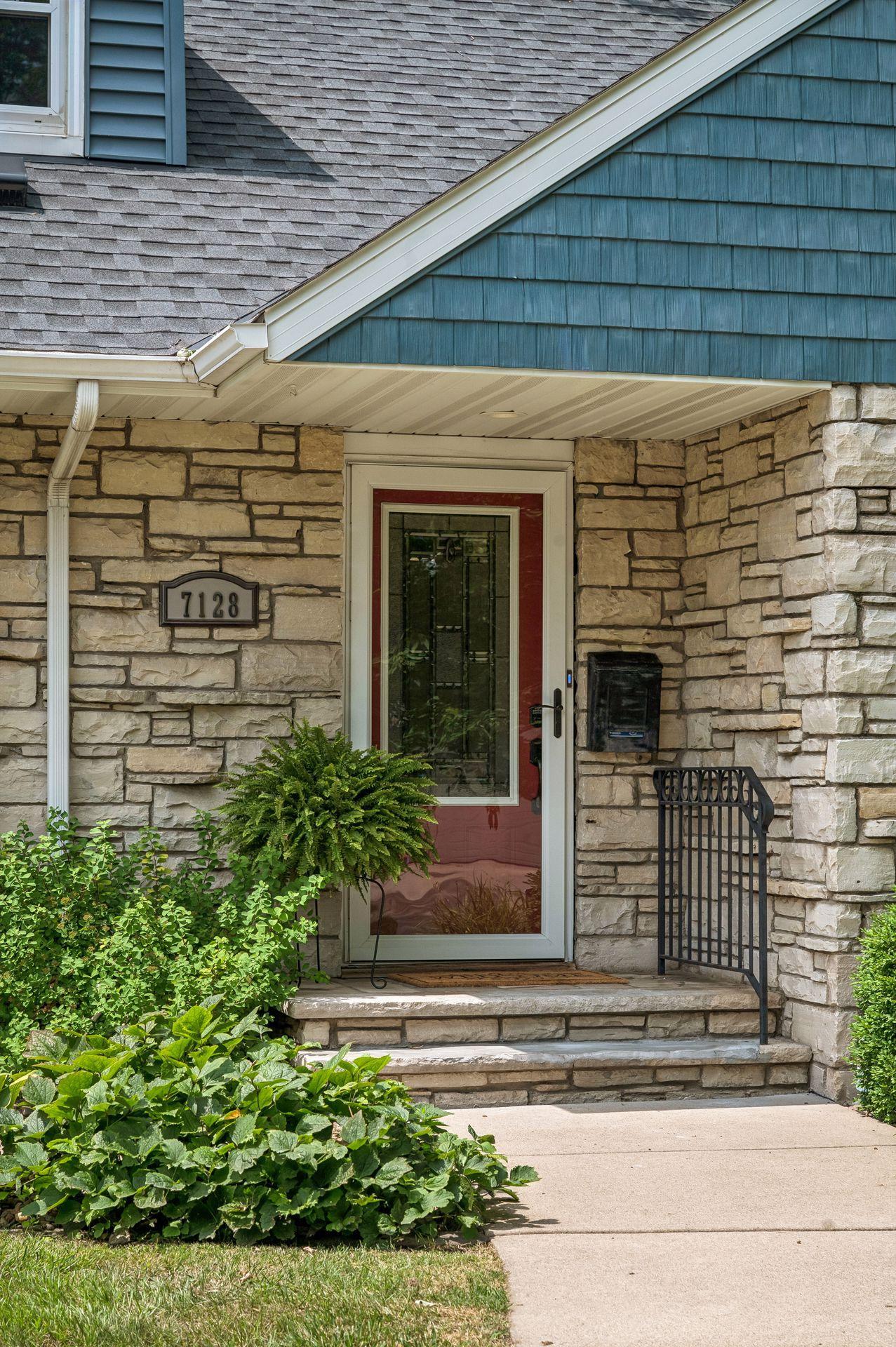 An inviting front entrance with stone and new concrete walkway