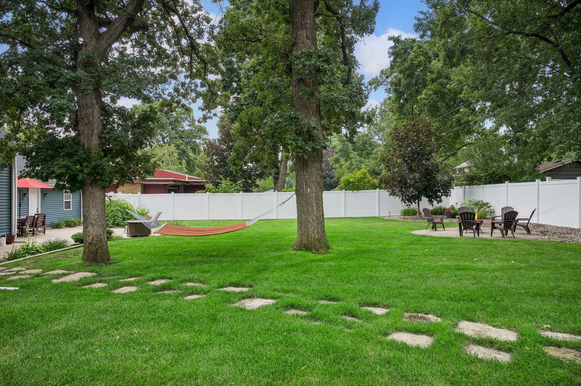 The beautiful landscaped backyard is ready for relaxation with an fire pit ring