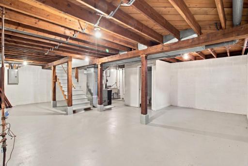 Lower level. Unfinished lower level with poured concrete floor, painted block walls, exposed joists, and overhead lighting.