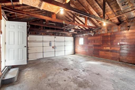 Garage interior. Double overhead door, wood plank walls, and a service door to the yard.