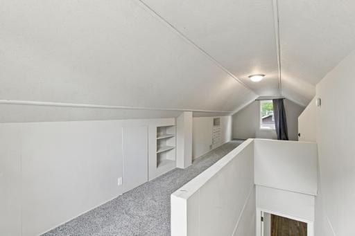 Upper level. Sloped ceilings, carpet, and built-in knee wall shelving.
