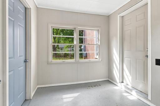Breezeway. Breezeway between the house and garage with painted wood plank walls, double window, and exterior service door.