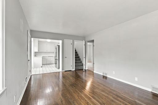 Living and dining area. Hardwood flooring with open sightlines to the kitchen and access to the stairway.