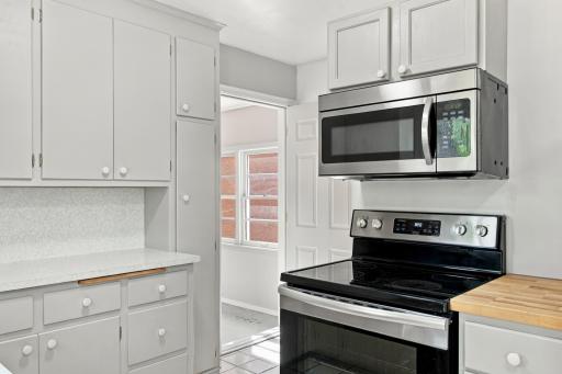 Kitchen. Floor to ceiling pantry cabinetry, stainless steel range and over-the-range microwave, and butcher block counter accents.