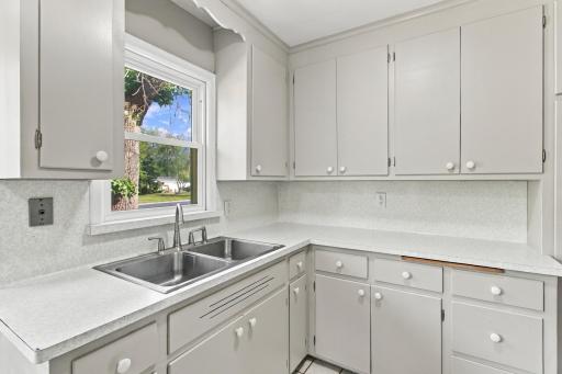 Kitchen. L-shaped counter run with a double basin sink under the window and butcher block counter accent.