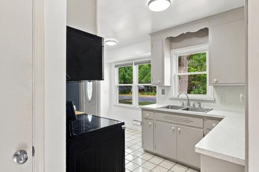 Kitchen. Sink wall with a double window above the stainless sink, light speckled countertops, and a stainless steel electric range with hood.