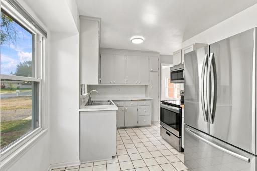 Kitchen. Full galley run viewed from the dining side, with stainless steel refrigerator and range over ceramic tile.