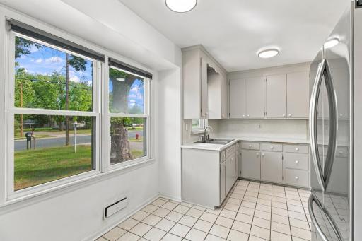 Kitchen. Wide picture window facing the front yard, ceramic tile flooring, and a stainless steel French door refrigerator.