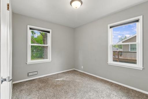 Bedroom. Carpet and two windows on adjacent walls.