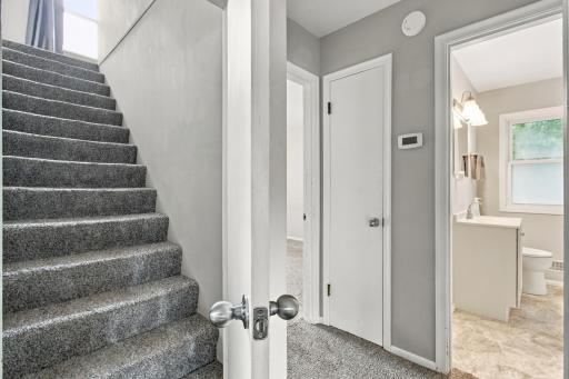 Stair hall. Carpeted stairway to the upper level, with the main floor full bath and bedroom doors off the hall.