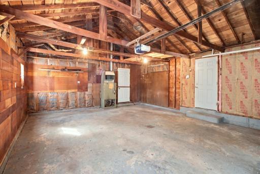 Garage interior. Automatic opener, wood plank walls, and a service door.