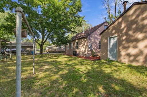 Backyard. Looking toward the house across open lawn under mature shade trees.