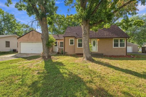 Exterior. Stucco elevation with the two-car garage and mature trees over the lawn.