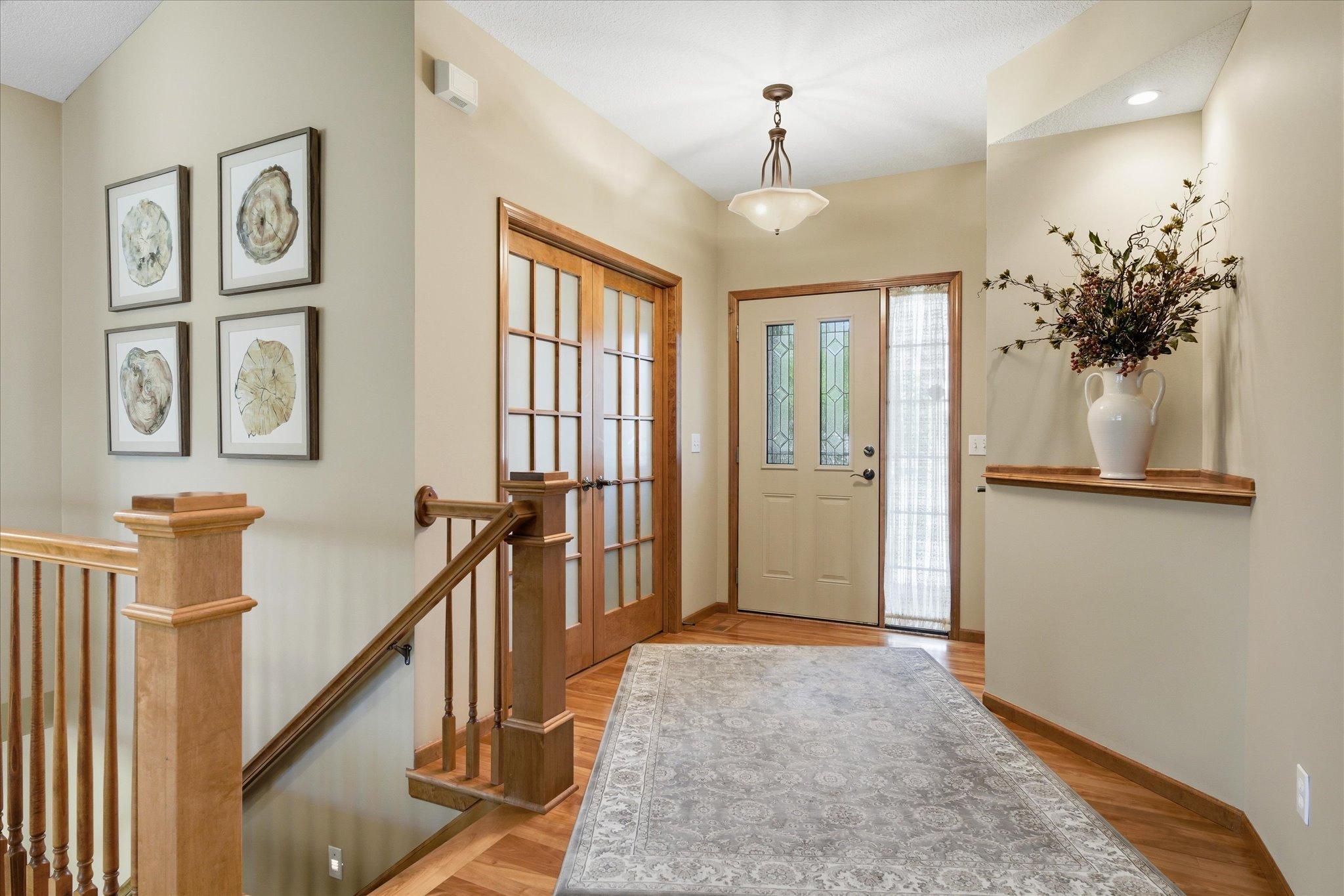 Grand foyer welcomes you with soaring ceilings, warm hardwood floors, decorative glass front door, and elegant French doors leading to the main-level office/flex room.