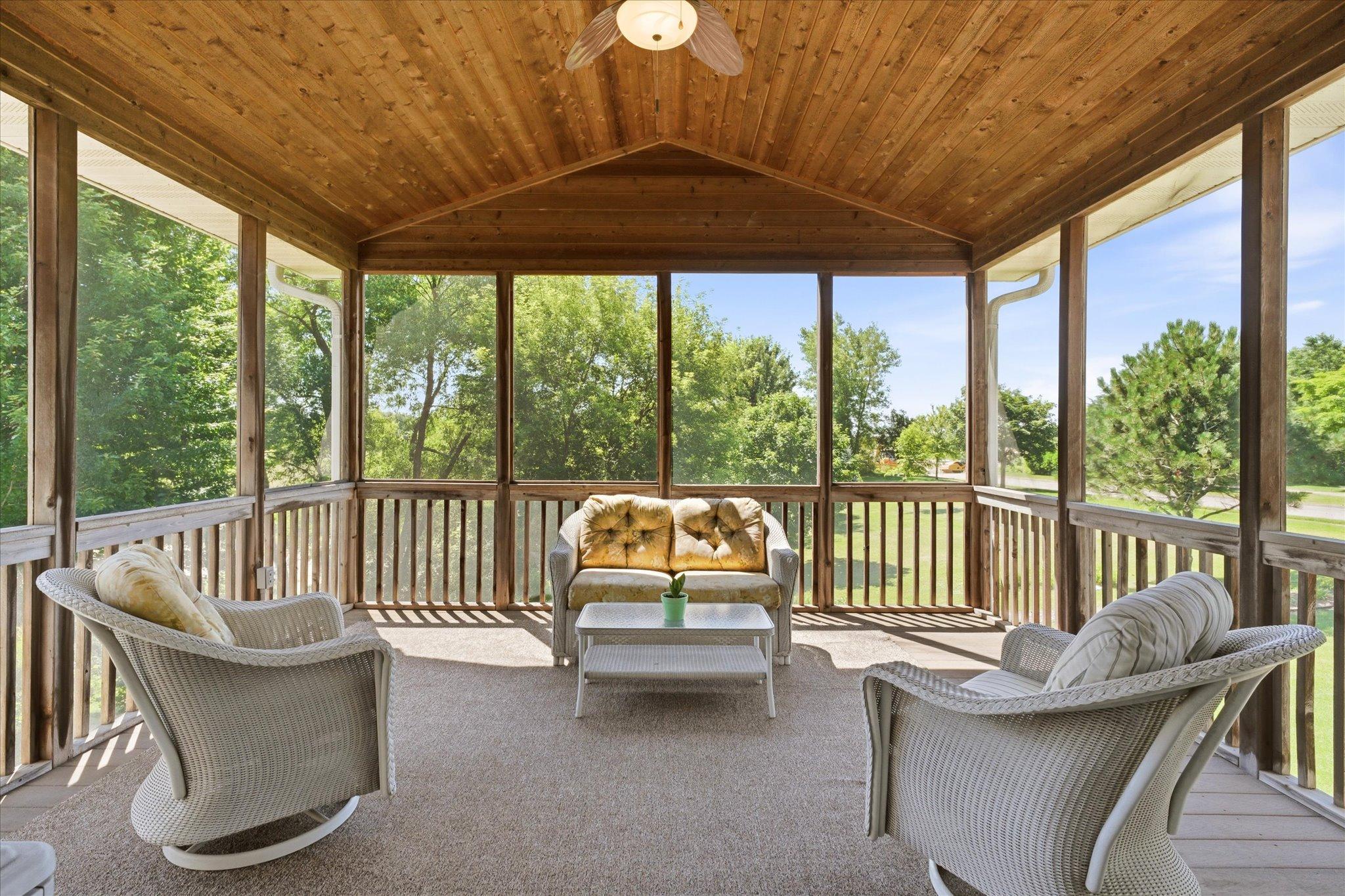 Relax and unwind in the spacious screened three-season porch featuring a beautiful tongue-and-groove wood vaulted ceiling, ceiling fan, and peaceful nature views.