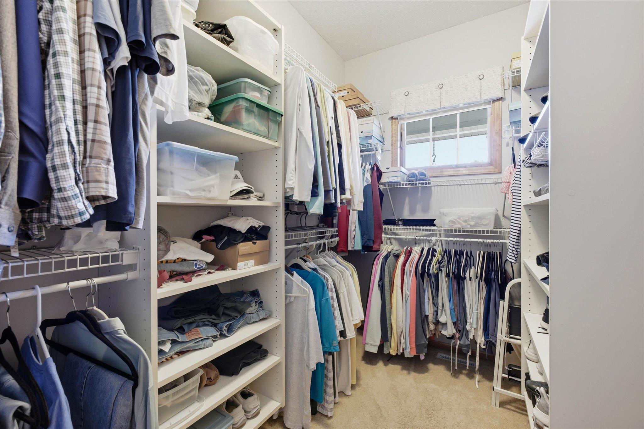 Exceptional walk-in closet offers custom organization with extensive shelving, multiple hanging areas, and plenty of space for clothing, shoes, and accessories.