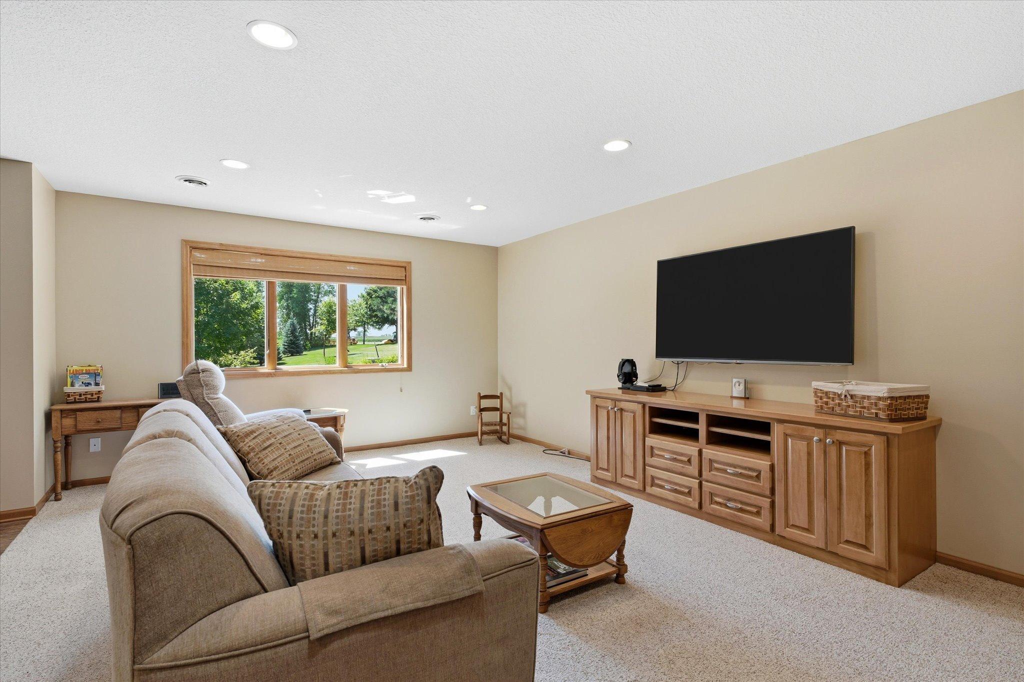 Spacious lower-level family room offers abundant space for everyday living and entertaining, complete with plush carpeting, recessed lighting, and an open-concept design.