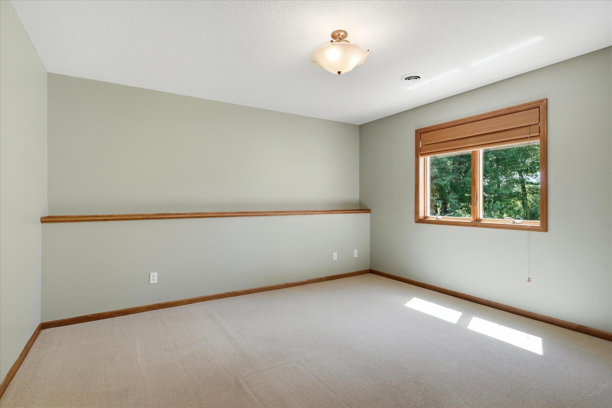 Spacious lower-level bedroom #2 offers plush carpeting, abundant natural light, neutral finishes