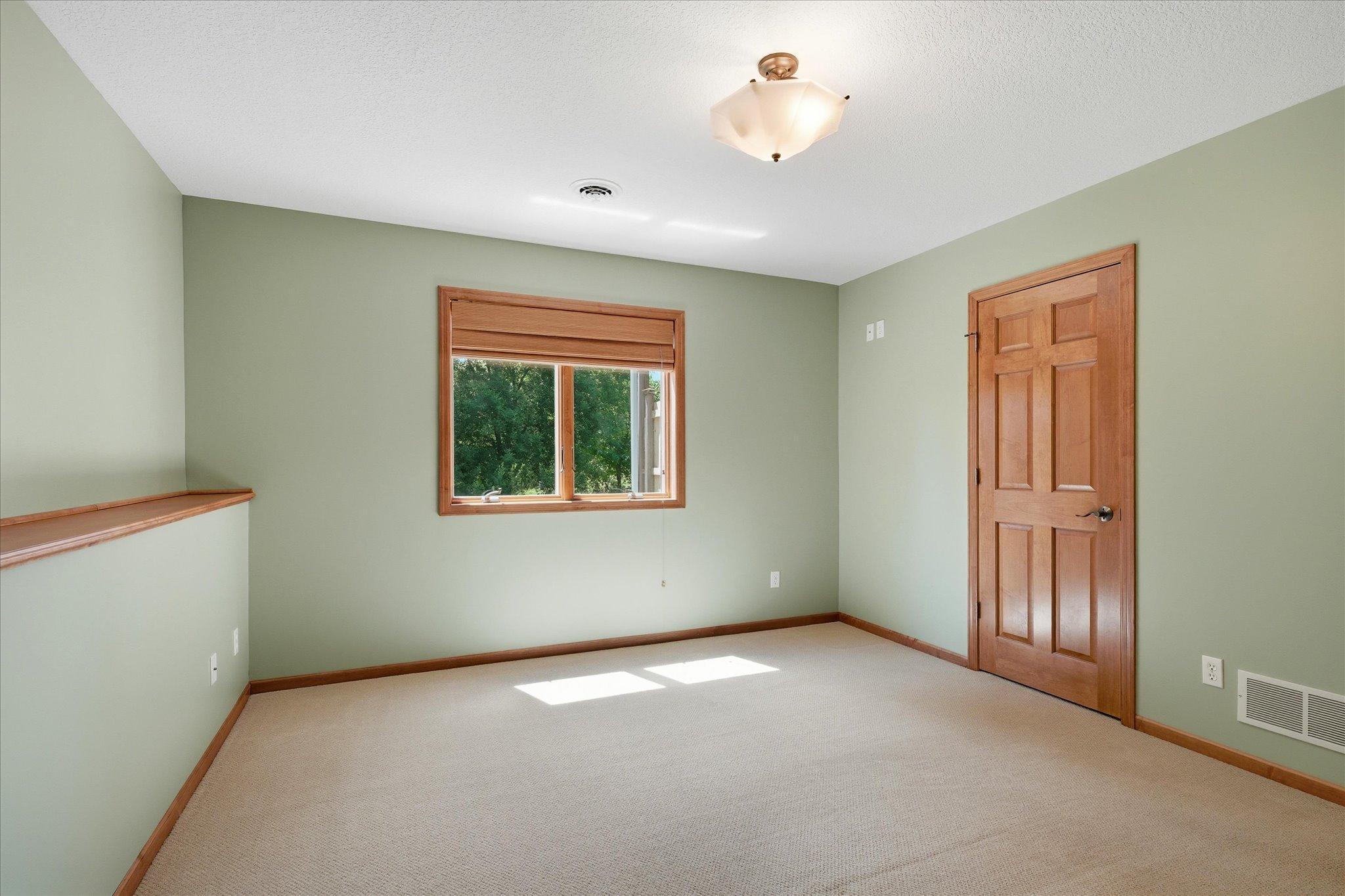 Another view of the generously sized lower-level bedroom #2 showcasing the large window, spacious layout, and walk-in closet.