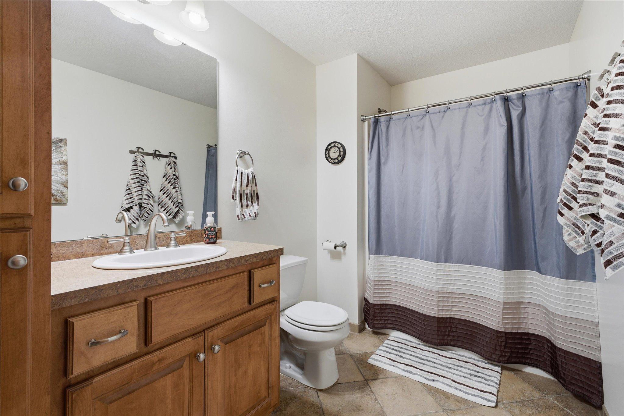 Full lower-level bathroom features an oversized vanity with abundant storage, durable tile flooring, and a tub/shower combination.
