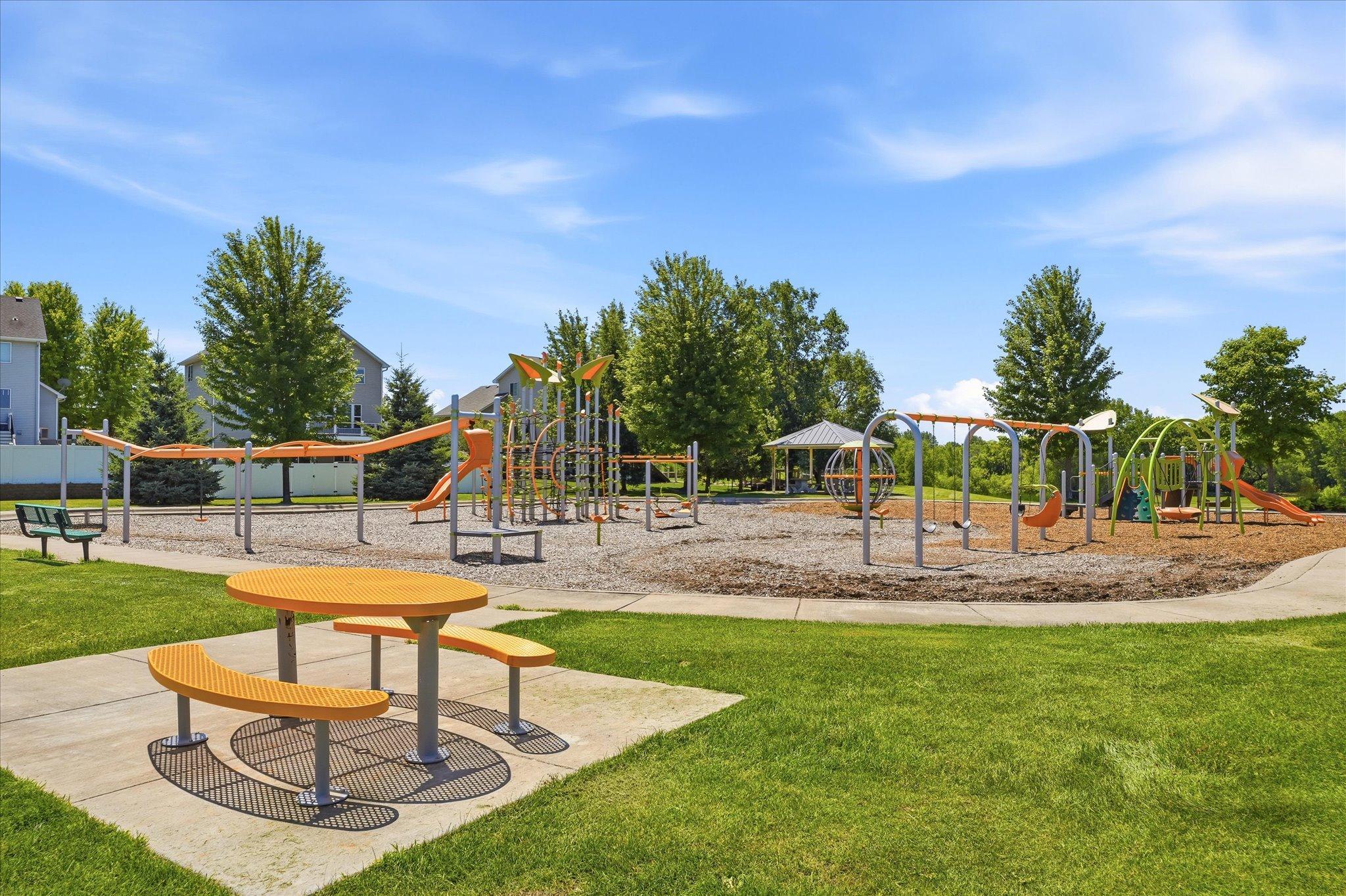 Large community playground features modern play equipment, swings, climbing structures, and picnic seating, creating the perfect place to spend time outdoors.