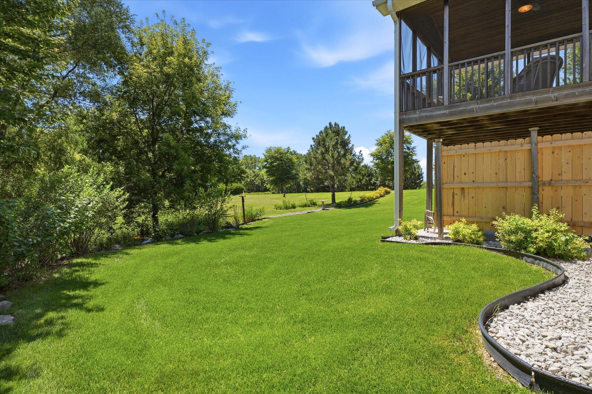 Beautifully landscaped backyard offers a lush lawn, mature trees, and peaceful views, creating the perfect setting to relax and enjoy the outdoors.