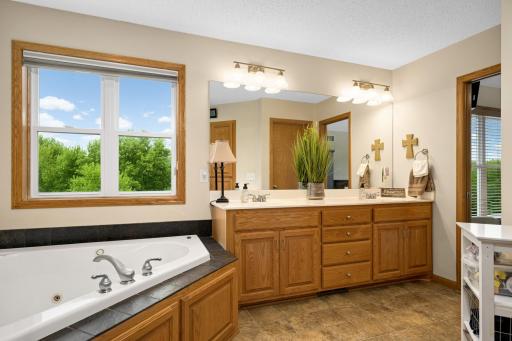 Primary bathroom with a dual vanity sink, large soaking tub, and separate shower.