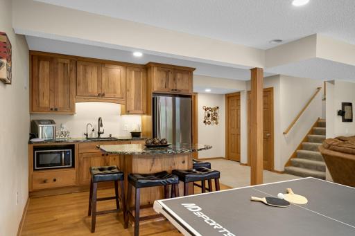 Updated bar area in the lower level with custom wood cabinets, large island, and sink.