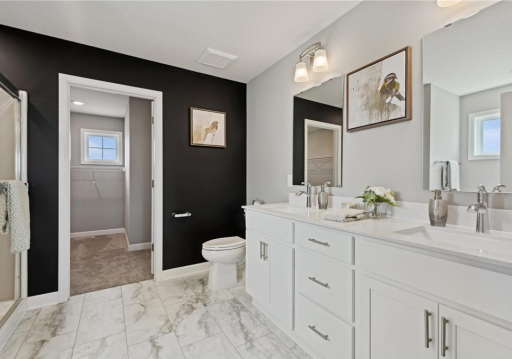 This photo is of the home when it was a decorated model. There is a double sink vanity - luxury height - located in the primary ensure bath beaming with quartz countertops.