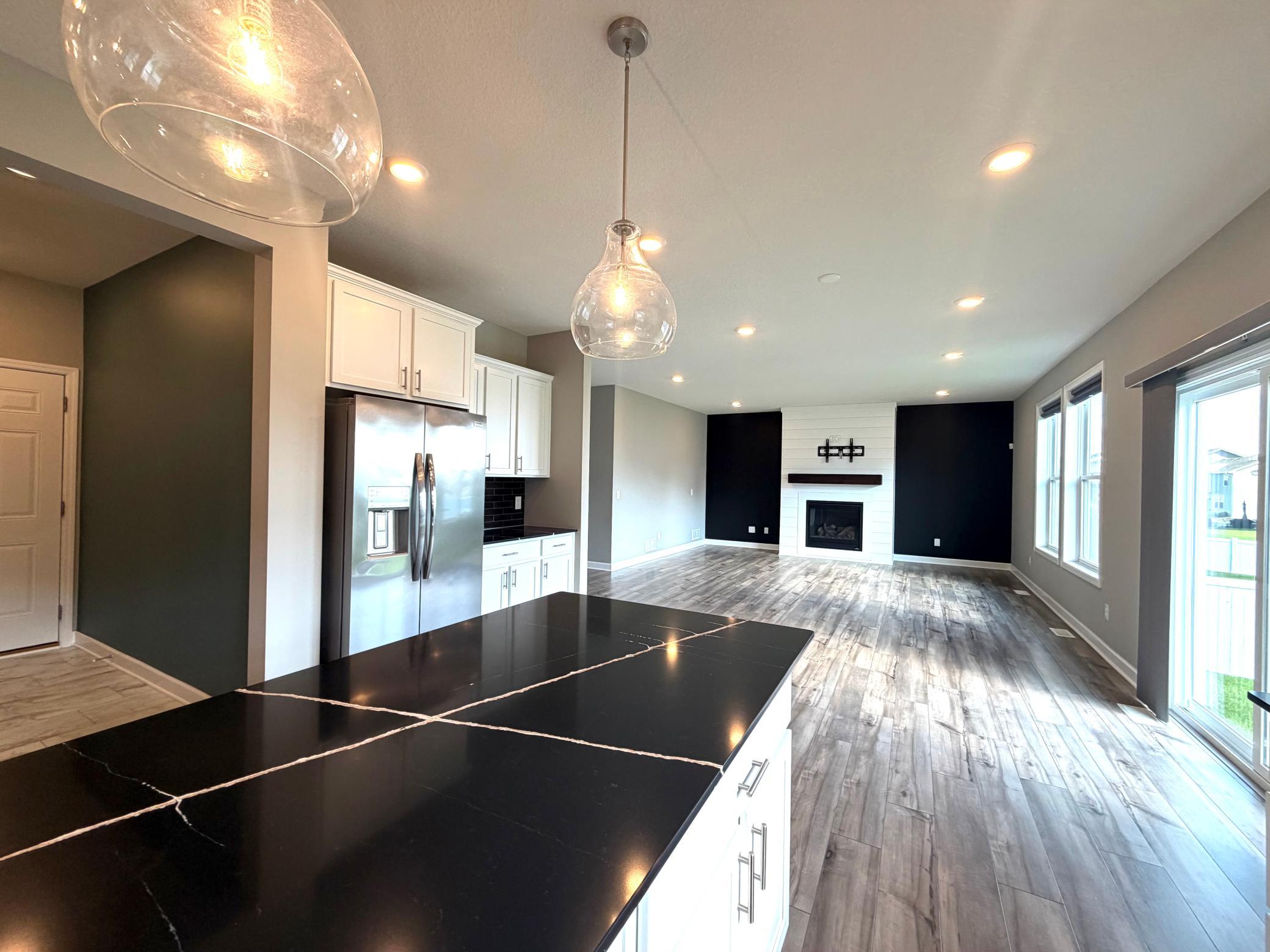 Photo of the actual home with staging removed. A ton of space on the main floor with a great amount of natural light beaming in. The mudroom is conveniently located off of the kitchen to the left. The lighting shown in this photo is included.