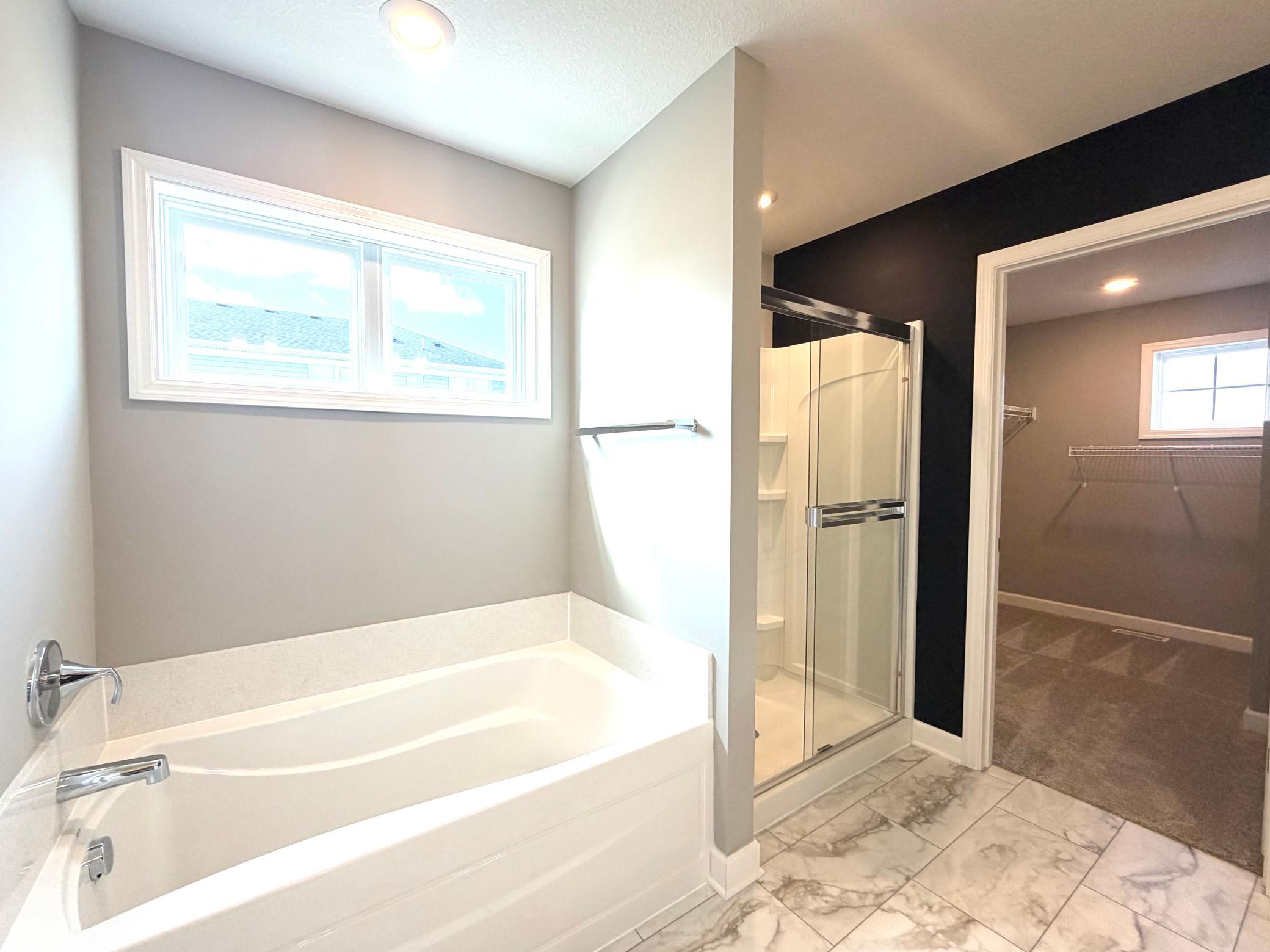 Photo of the actual home with model staging removed. The primary ensuite bath is its own private retreat as it offers a beautiful picture window, large soaking tub and spacious walk-in shower.