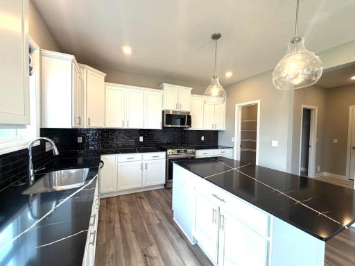 Be impressed with this state of the art & custom finished luxury kitchen. The stunning highly upgraded quartz countertops & accented backsplash make this kitchen a show stopper! There is a large walk in pantry & direct access to the mudroom.