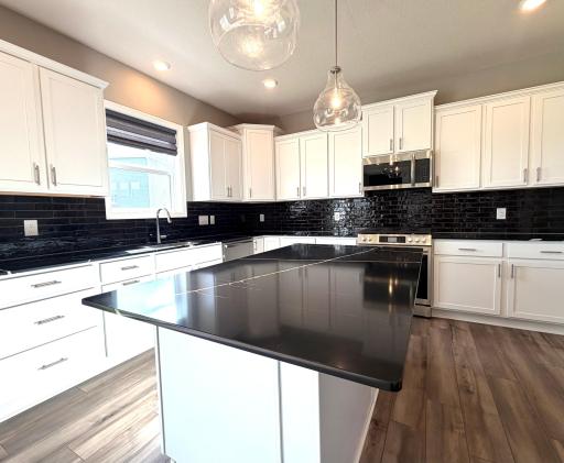 Enjoy all of the modern amenities one could desire! This amazing kitchen offers a oversized island, beautiful white soft closing cabinetry, all SS appliances including the gas range & direct vented microwave.