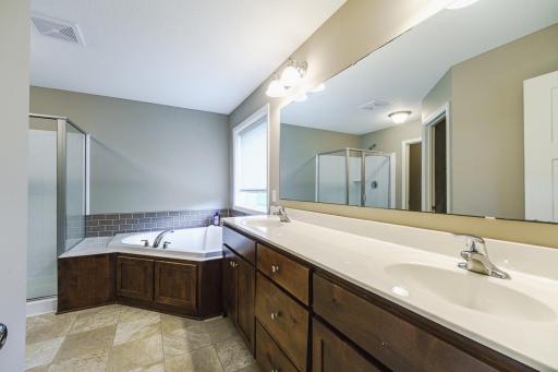 There is a full en suite bath with dual sinks, a jetted tub with a tile backsplash, and a tile walk-in shower.