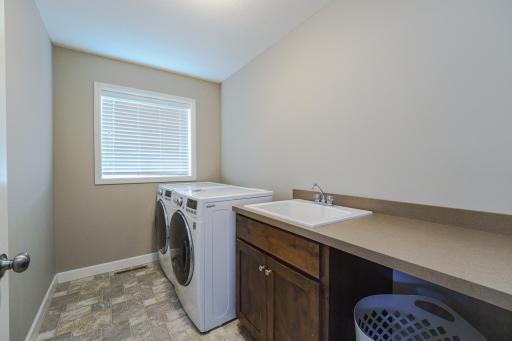 The second floor laundry room has cabinetry, a folding counter a utility sink and a bright window. The washer and dryer are included.