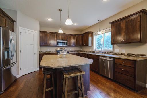 Wide-plank hardwood flooring runs throughout and contrasts against white doors and trim. In addition to abundant cabinetry with deep storage drawers, there is a pantry.