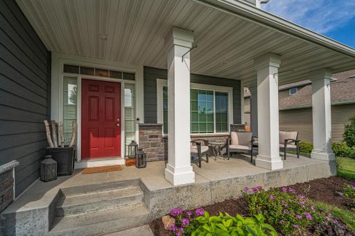 The charming CONCRETE front porch has white columns and stone facing.