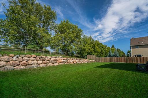 Private backyard with a rock wall and mature trees!