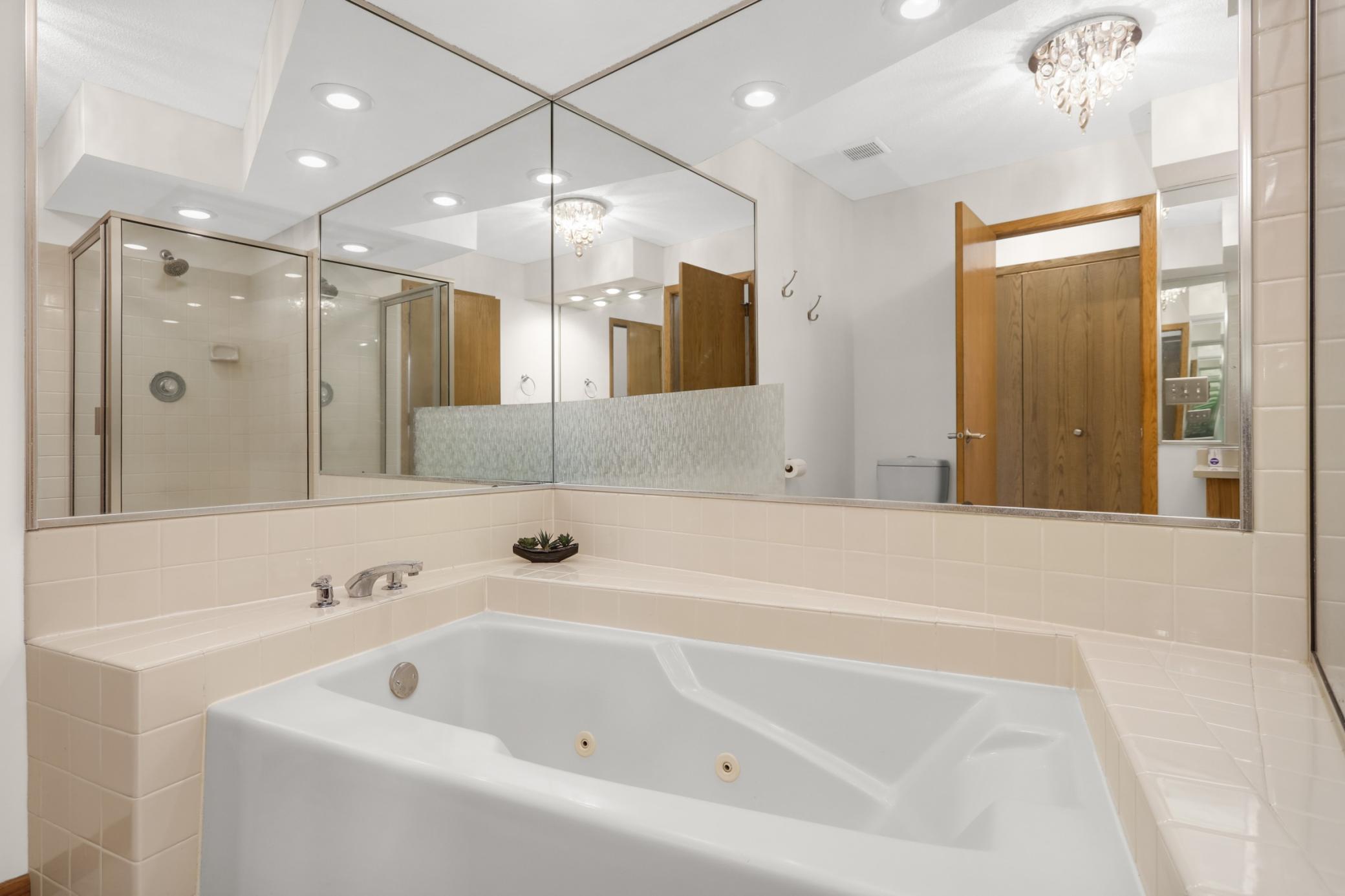 The jetted tub creates a spa like feeling with space surrounding the tub for decor accents and candles.
The mirror reflection shows the walk in shower located to the right of the tub.