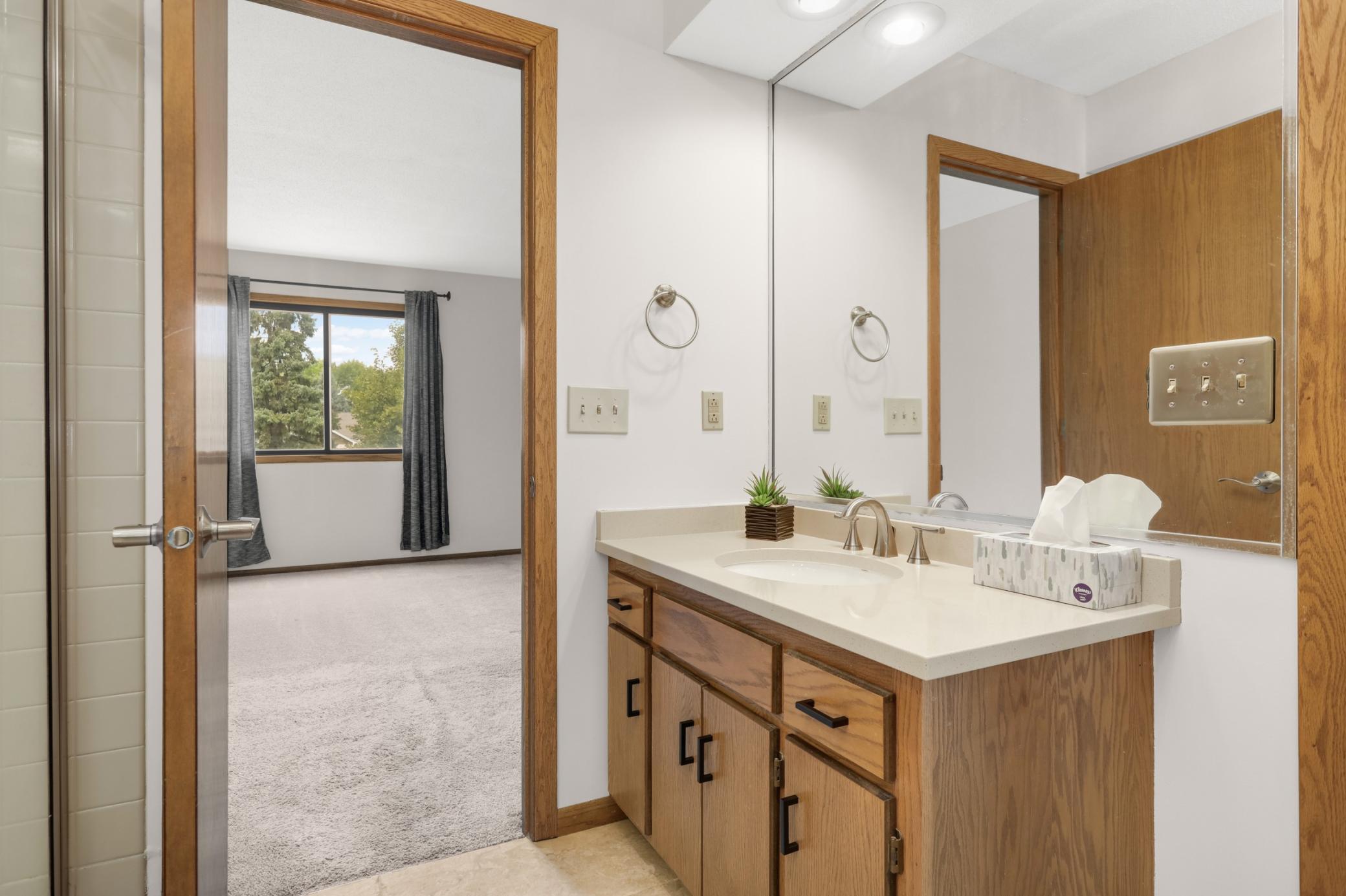 The bathroom showing the direct access door to the primary bedroom. The bathroom has two doors; one with access from the hallway and the other from the primary bedroom. The walk in shower is on the left.