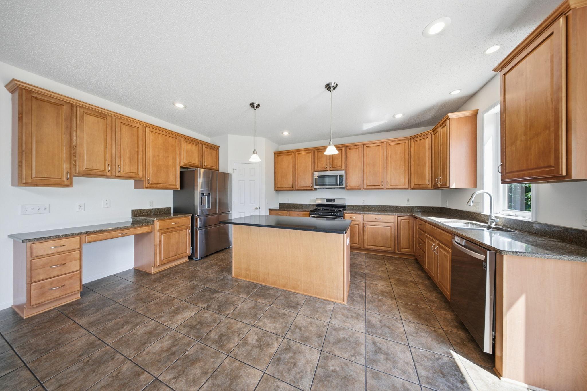 The kitchen is complete with a center island, pantry, and space for an eat-in table.